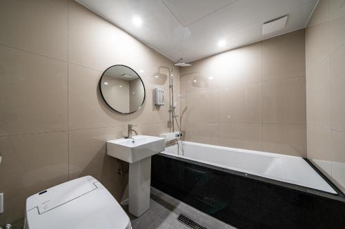 a bathroom with a toilet and a sink and a tub at Seosan Hotel Posto in Seosan