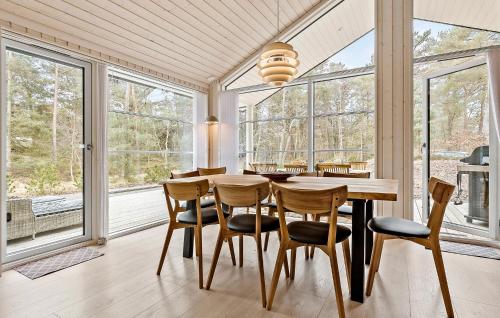 a dining room with a table and chairs and windows at Lovely Home In Nexø With Sauna in Neksø