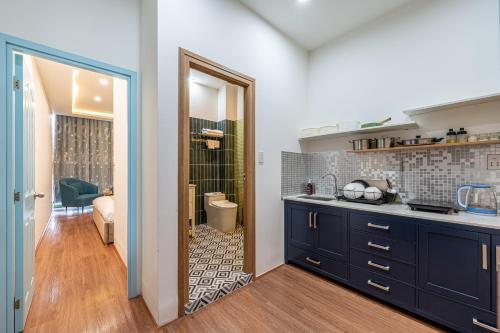 a kitchen with blue cabinets and a walk in shower at Palas House By Cozrum in Ho Chi Minh City