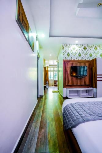 a hotel room with a bed and a tv on the wall at The Bunksters Mcleodganj, Dharmkot in McLeod Ganj