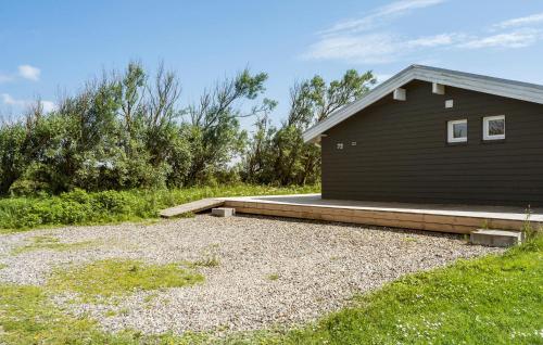 a black building with a porch next to a yard at Stunning Home In Ringkøbing With Sauna in Ringkøbing
