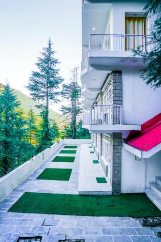 a white building with a balcony and green grass at The Bunksters Mcleodganj, Dharmkot in McLeod Ganj