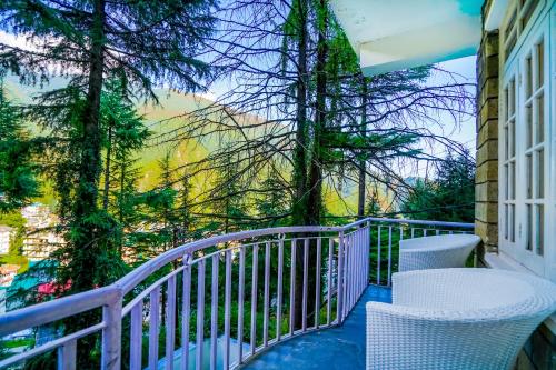 a balcony with white chairs and a view at The Bunksters Mcleodganj, Dharmkot in McLeod Ganj