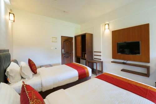 a hotel room with two beds and a flat screen tv at The Sanihara Hotel & Resort in Vythiri
