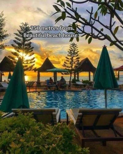 a pool with chairs and umbrellas in a resort at Lanta Beautiful beach house in Ko Lanta