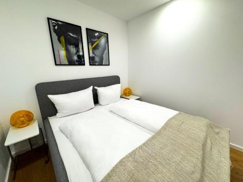 a white bed in a room with two pictures on the wall at ma suite - urban apartment city center - private parking 2-4P in Augsburg