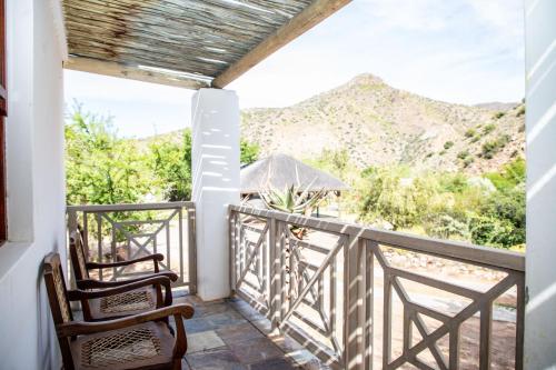 a balcony with two chairs and a view of the mountains at Bushman Valley in Prince Albert