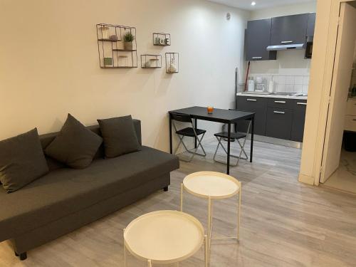 a living room with a couch and two tables and a kitchen at La Ciotat Chez Hugo confortable studio clim, wifi, parking, centre ville, commerces, port, plages à pieds in La Ciotat
