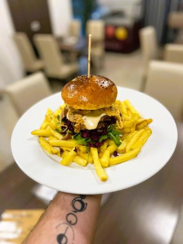 a person holding a plate with a sandwich and french fries at PENZION U BRÁZDŮ in Ivančice