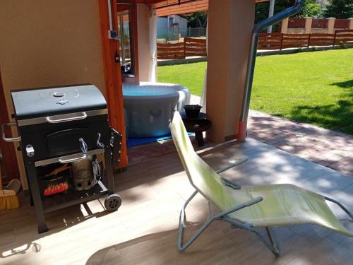 a green chair next to a stove and a tub at Hollós-patak Vendégház in Komlóska