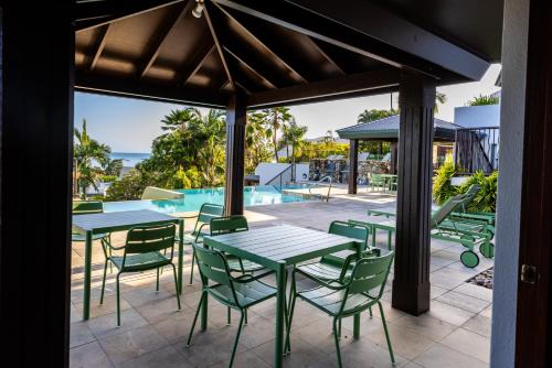 a patio with tables and chairs and a pool at Aqua on the Edge in Airlie Beach