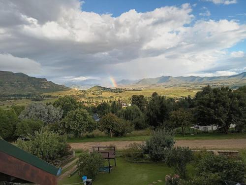 a rainbow in the sky over a field with a bench at Akzente in Clarens