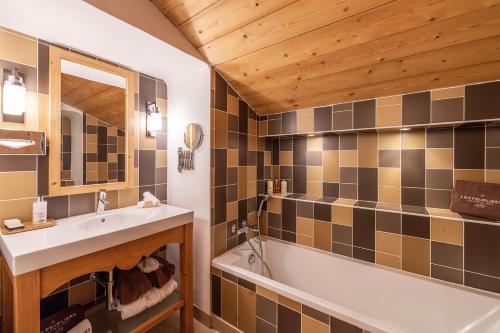 a bathroom with a sink and a bath tub at La Maison Hôtel Les Peupliers in Courchevel