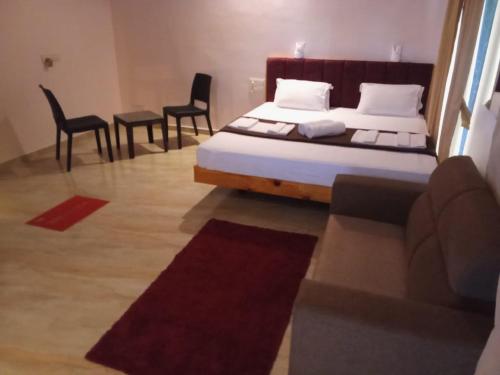 a bedroom with a bed and a table and chairs at Hotel Town Pride , Ganpatipule in Ganpatipule
