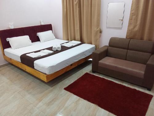 a bedroom with a bed and a couch at Hotel Town Pride , Ganpatipule in Ganpatipule