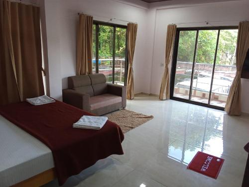a bedroom with a bed and a chair and a window at Hotel Town Pride , Ganpatipule in Ganpatipule
