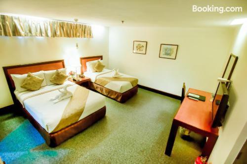 a hotel room with two beds and a desk at Rajah Park Hotel by Hiverooms in Cebu City