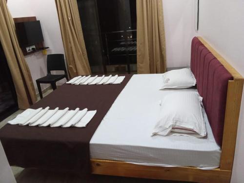 a bed with white pillows on it in a room at Hotel Town Pride , Ganpatipule in Ganpatipule