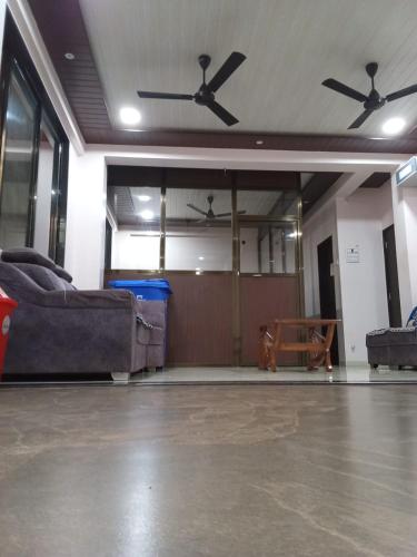 a living room with couches and a ceiling fan at Hotel Town Pride , Ganpatipule in Ganpatipule