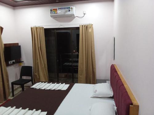 a bedroom with a bed and a window with a air conditioner at Hotel Town Pride , Ganpatipule in Ganpatipule