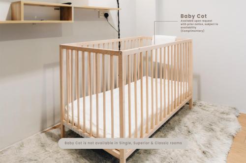 a wooden crib in a room with a rug at Santa Grand Hotel East Coast a NuVe Group Collection in Singapore