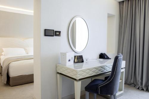 a bedroom with a desk with a mirror and a bed at Tresor Le Palais Timisoara, Curio Collection by Hilton in Timişoara