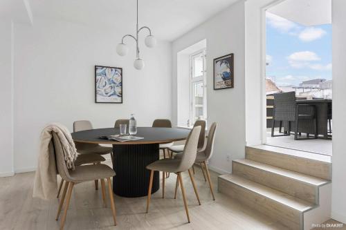 a dining room with a table and chairs and a window at Premium High-Street Home w Large Private Terrace in Aarhus