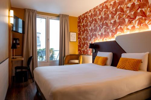 a hotel room with a large white bed with orange pillows at Kyriad Paris 10 - Canal Saint Martin - République in Paris