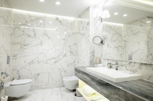 a white bathroom with a sink and a toilet at Tresor Le Palais Timisoara, Curio Collection by Hilton in Timişoara