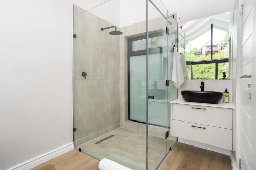 a bathroom with a glass shower with a sink at Wild Sage - Wilderness Cottage in Wilderness