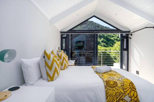 a bedroom with a large bed with yellow and white pillows at Wild Sage - Wilderness Cottage in Wilderness