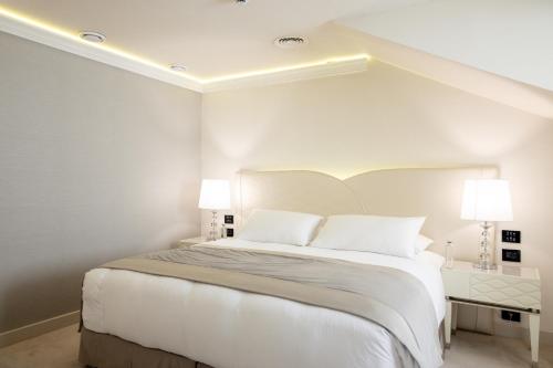 a white bedroom with a large bed with two lamps at Tresor Le Palais Timisoara, Curio Collection by Hilton in Timişoara