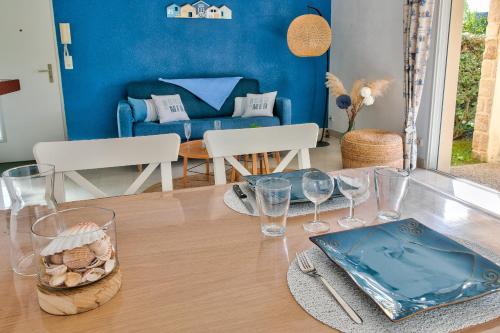 une salle à manger avec une table, des verres et un canapé dans l'établissement À 400m de la mer appartement avec terrasse pour 2, à Fouesnant