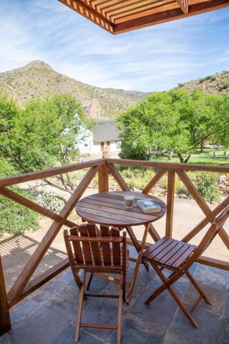 a wooden table and chairs on a balcony with mountains at Bushman Valley in Prince Albert