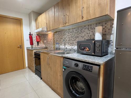 a kitchen with a washing machine and a microwave at ASHRI HH Spacious Studio in May Residence JVC in Dubai