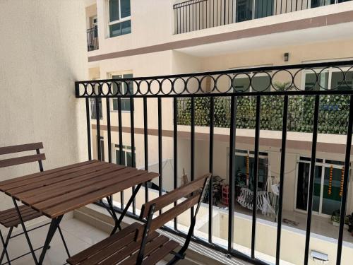 a balcony with a wooden bench and a building at ASHRI HH Spacious Studio in May Residence JVC in Dubai