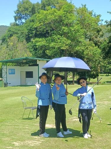 three girls standing under an umbrella in a field at The European Chiang Mai in Chiang Mai