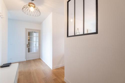 Cette chambre est dotée d'un mur blanc et d'un lustre. dans l'établissement La Tournette - Appartement confortable à deux pas du lac, à Annecy