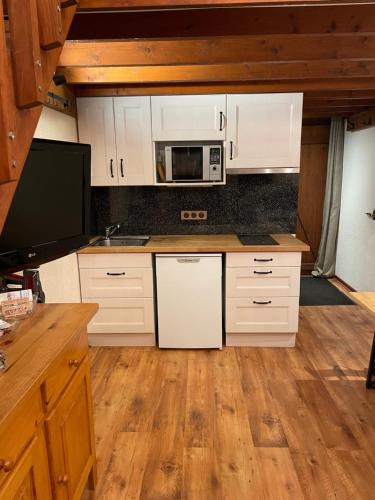 a kitchen with white cabinets and a microwave at Petit chalet cosy prêt des pistes in Bolquere Pyrenees 2000