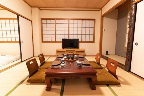 a room with a table and chairs and a tv at 大吉屋本館 ワンフロア貸切部屋 名駅離れ in Nagoya