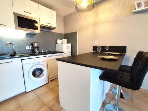 - une cuisine avec une table et un lave-linge/sèche-linge dans l'établissement La Noria - Confort et Facilité - Parking, à Aucamville