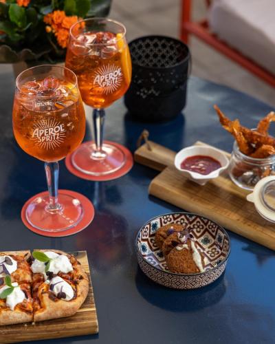 a table with two glasses of drinks and a pizza at Hilton Garden Inn Florence Novoli in Florence