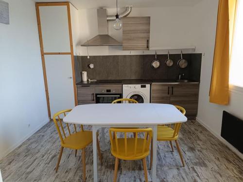 Una cocina con una mesa blanca y sillas amarillas. en Dans la brise du Rhône, en Arles
