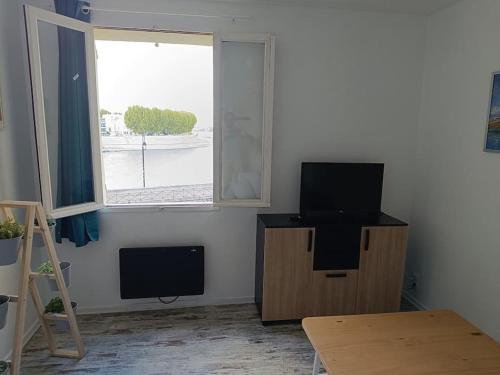 Una sala de estar con televisión y una ventana. en Dans la brise du Rhône, en Arles