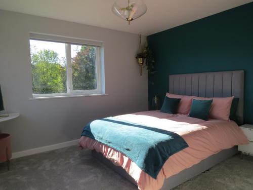 a bedroom with a bed with a green wall and a window at Bradleigh Down Holidays Apartment with Private Pool and Hot Tub in Tiverton