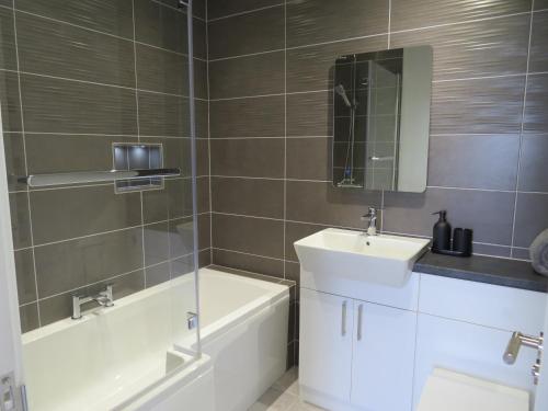 a bathroom with a tub and a sink and a bath tubermott at Bradleigh Down Holidays Apartment with Private Pool and Hot Tub in Tiverton