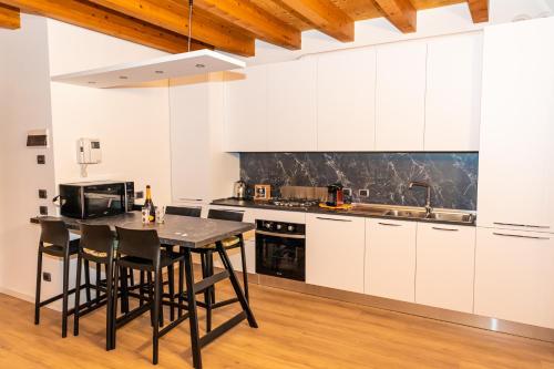 a kitchen with white cabinets and a wooden floor at La Casa di Lella in residence con piscina in Paratico