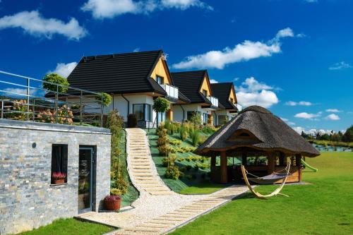 a house with a thatch roof and a gazebo at Słoneczne Chatki in Knurów