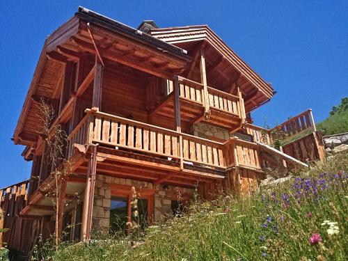 une grande maison en bois avec une terrasse sur une colline dans l'établissement Prestigious Chalet with Pool & Hot tub, Mountain Views for 19 Guests, à Vars