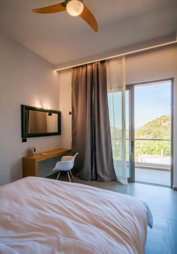 a bedroom with a bed and a desk and a window at Archontissa's House in mountainous village Drakona 22km from Chania in Dhrakóna